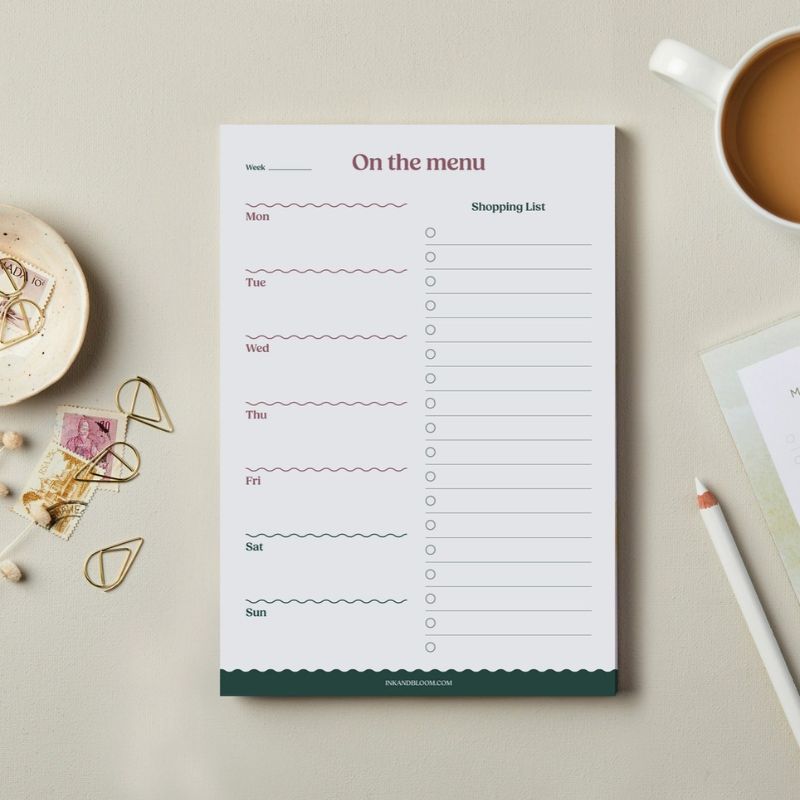 Meal Planner On the Menu Ink & Bloom format A5 posé sur un bureau - planificateur repas semaine motif vaguelettes vert & bordeaux