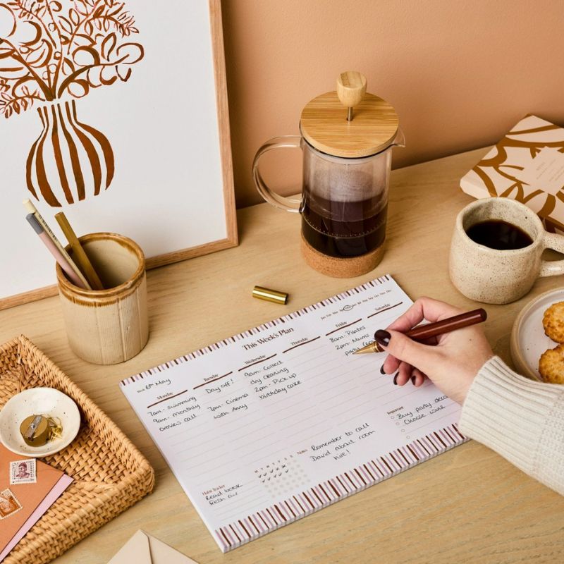 Planner semainier This Week's Plan Ink & Bloom rempli à la main sur un bureau avec cafetière et tasse - format A4 motif rayures