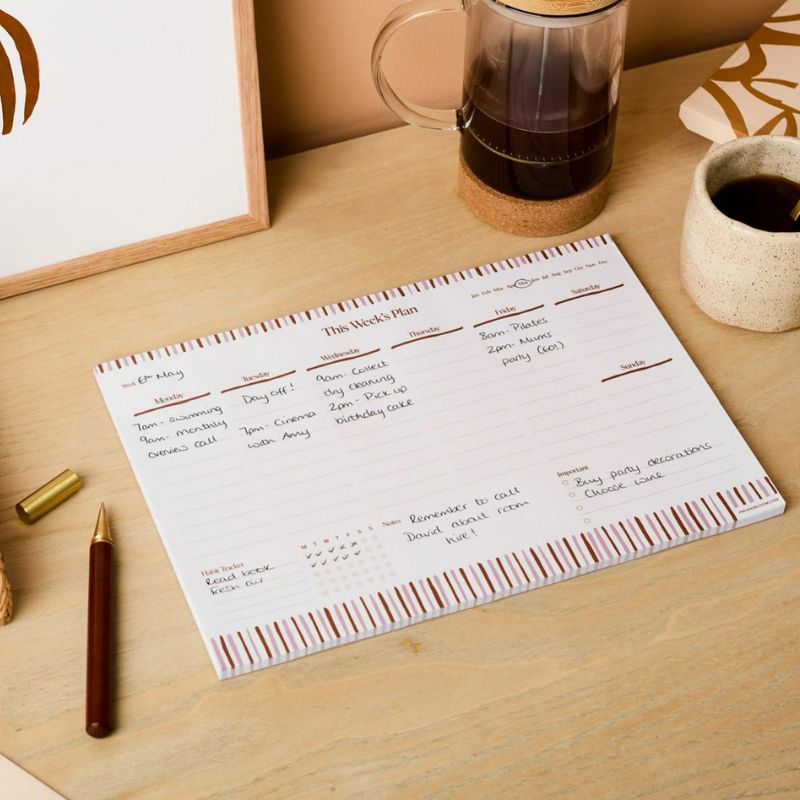 Planner semainier This Week's Plan Ink & Bloom rempli posé sur un bureau - habit tracker notes et section importante format A4