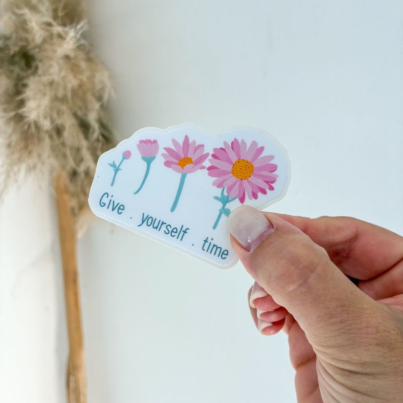 Sticker Give Yourself Time tenu à la main, message positif fleuri, papeterie Avril & Novembre